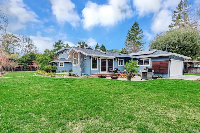 back of property with solar panels, concrete driveway, fence, an attached garage, and a yard