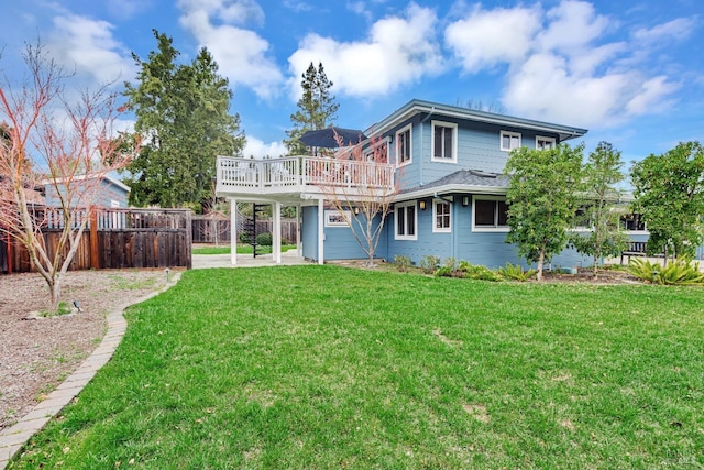 rear view of property featuring a yard, fence, and a deck