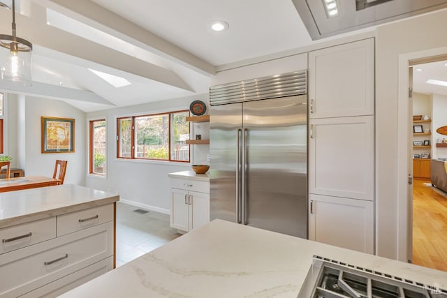 kitchen with recessed lighting, stainless steel built in fridge, light stone countertops, and white cabinetry