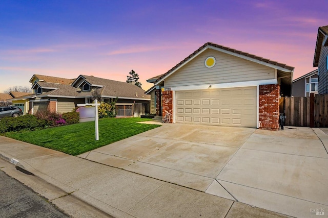 ranch-style house featuring a garage, concrete driveway, a lawn, fence, and brick siding