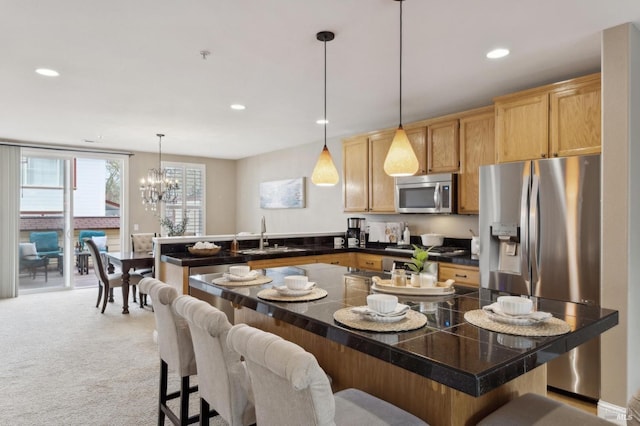 kitchen featuring a breakfast bar area, light carpet, a peninsula, appliances with stainless steel finishes, and tile counters