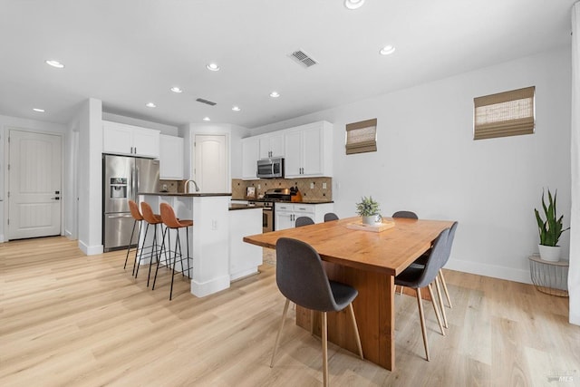 dining room featuring recessed lighting, baseboards, visible vents, and light wood finished floors