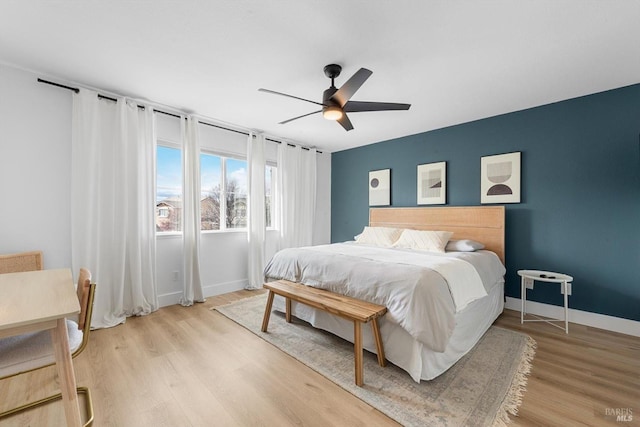 bedroom featuring a ceiling fan, light wood-style flooring, and baseboards