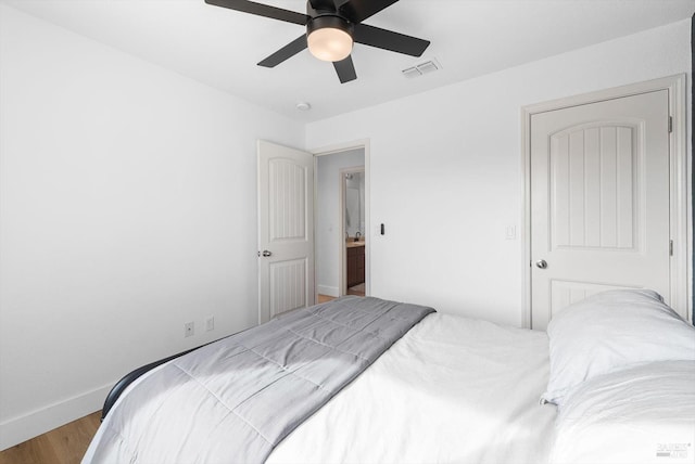 bedroom with a ceiling fan, visible vents, baseboards, and wood finished floors