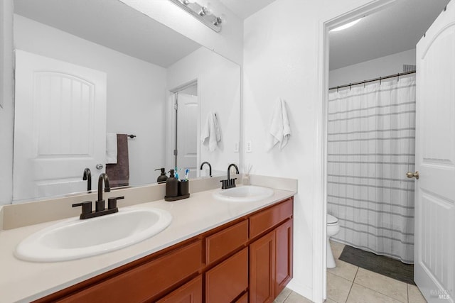 full bathroom with toilet, double vanity, a sink, and tile patterned floors