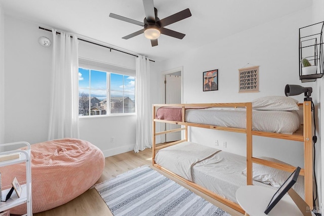 bedroom with a ceiling fan, baseboards, and wood finished floors