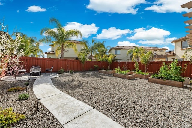 view of yard with a fenced backyard, a vegetable garden, and a patio