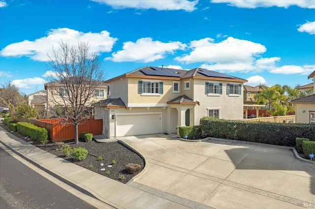 view of front of house featuring concrete driveway, solar panels, an attached garage, fence, and stucco siding