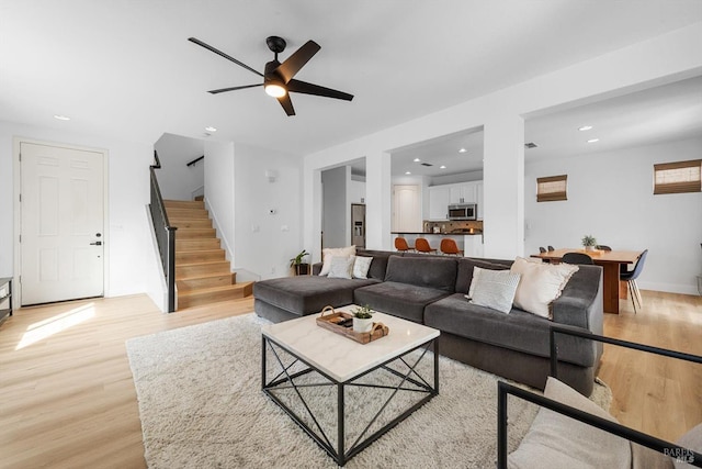 living area featuring light wood-style flooring, recessed lighting, and stairway