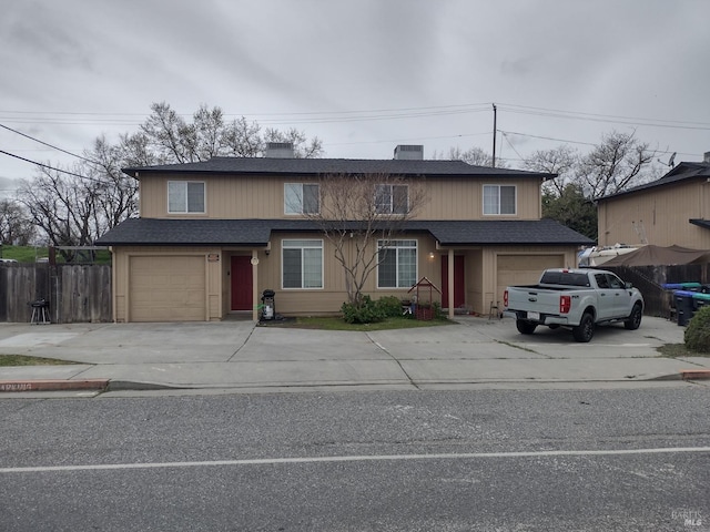 traditional-style home featuring driveway, roof with shingles, an attached garage, and fence