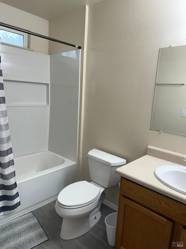 full bathroom featuring toilet, a textured wall, wood finished floors, and vanity