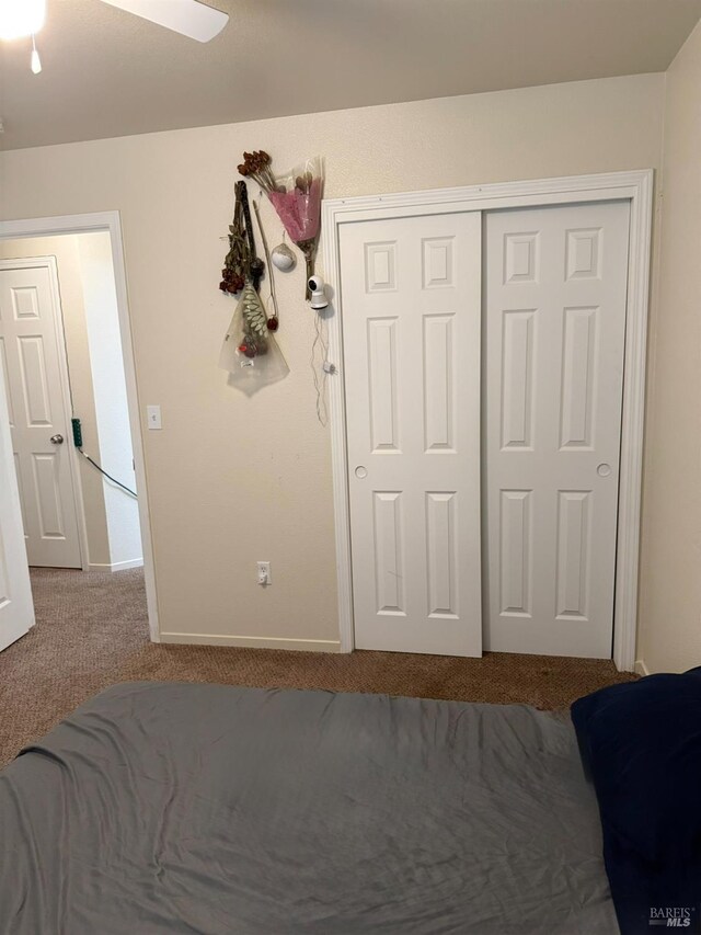 carpeted bedroom with a closet and baseboards