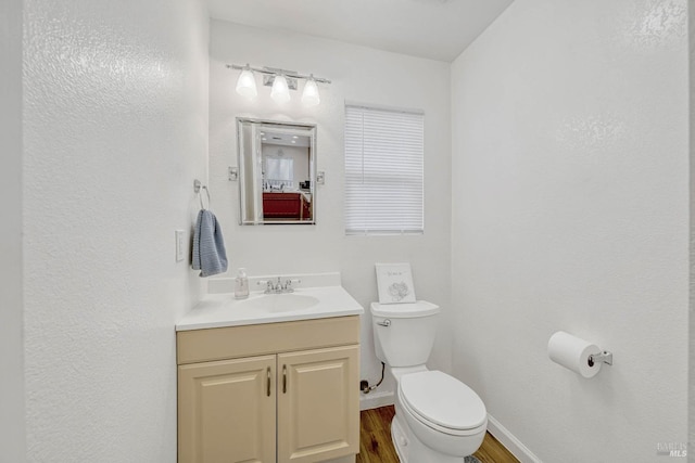 bathroom featuring vanity, wood finished floors, toilet, and baseboards