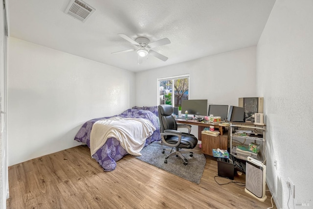 bedroom with a ceiling fan, visible vents, and wood finished floors