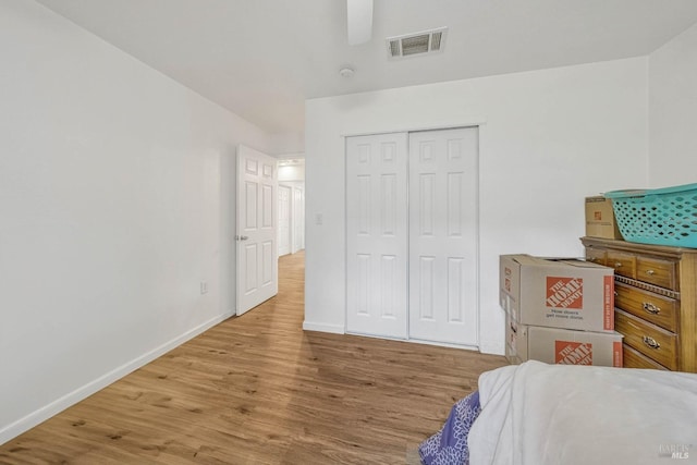 bedroom featuring a closet, visible vents, a ceiling fan, wood finished floors, and baseboards