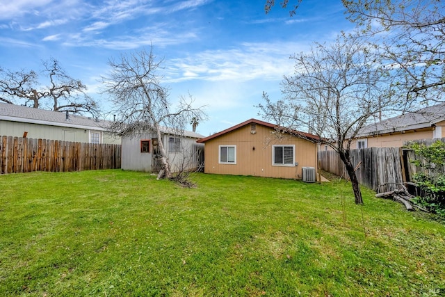 rear view of property with an outbuilding, a lawn, a fenced backyard, and central air condition unit