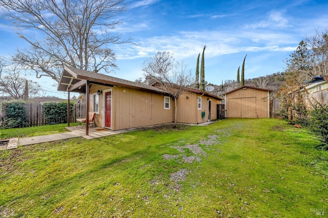 rear view of property with an outbuilding, a lawn, a patio area, a shed, and a fenced backyard