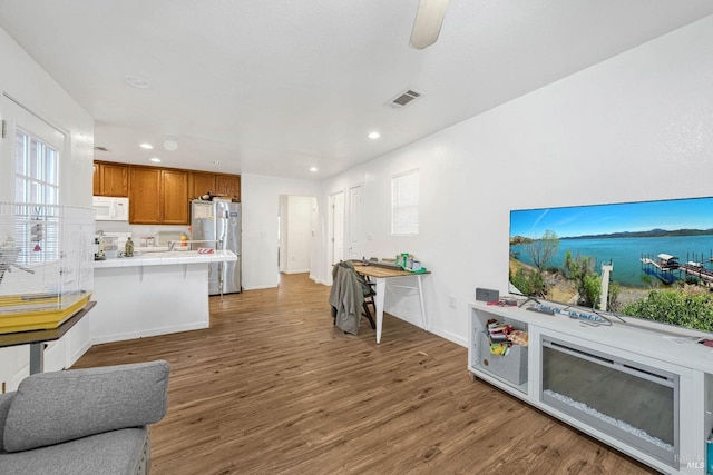 living room featuring baseboards, visible vents, wood finished floors, and recessed lighting