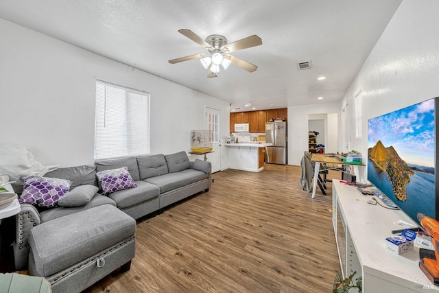 living room with light wood-type flooring, visible vents, ceiling fan, and recessed lighting