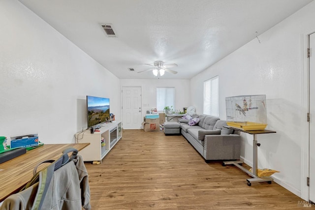 living area with light wood finished floors, ceiling fan, and visible vents