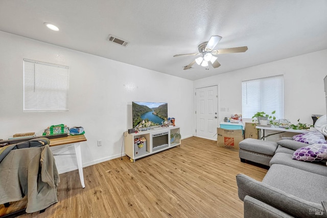 living area featuring light wood-style floors, visible vents, ceiling fan, and baseboards