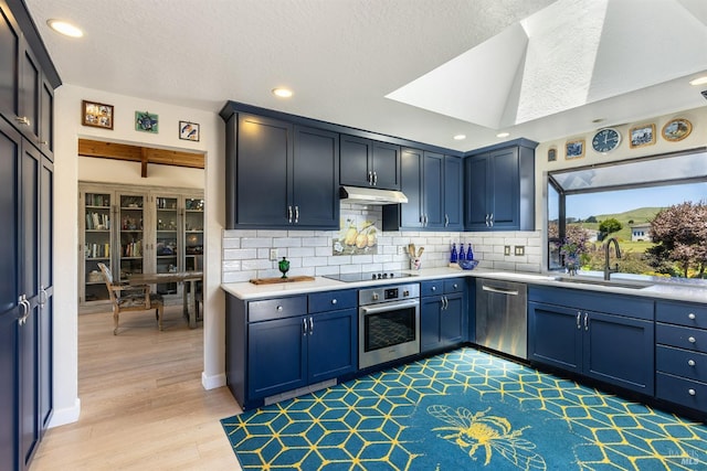 kitchen featuring under cabinet range hood, stainless steel appliances, light countertops, and a sink