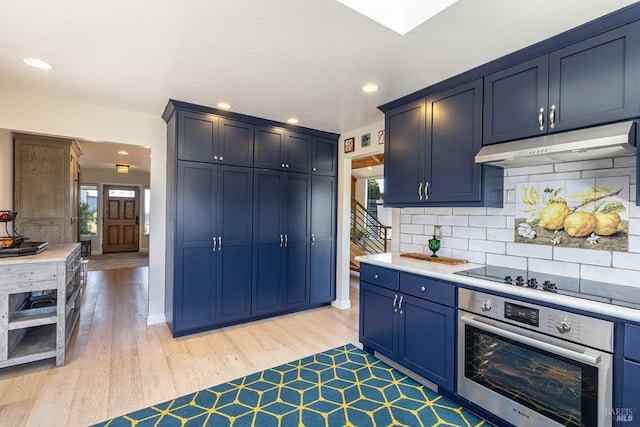 kitchen featuring plenty of natural light, under cabinet range hood, stainless steel oven, black electric stovetop, and blue cabinets