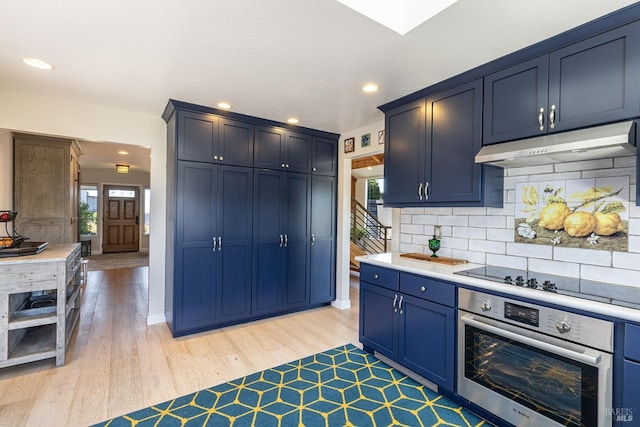 195 Condor Ct Unit 1061, Bodega Bay, CA 94923 - kitchen with stainless steel oven, under cabinet range hood, blue cabinets, black electric stovetop, and light wood-style flooring