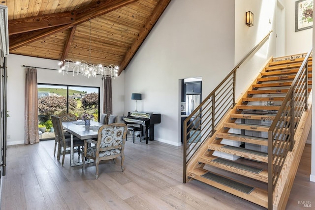 dining room featuring stairs, beam ceiling, baseboards, and light wood-type flooring