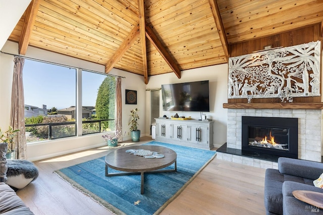 living area with wood ceiling, wood finished floors, vaulted ceiling with beams, and a tile fireplace