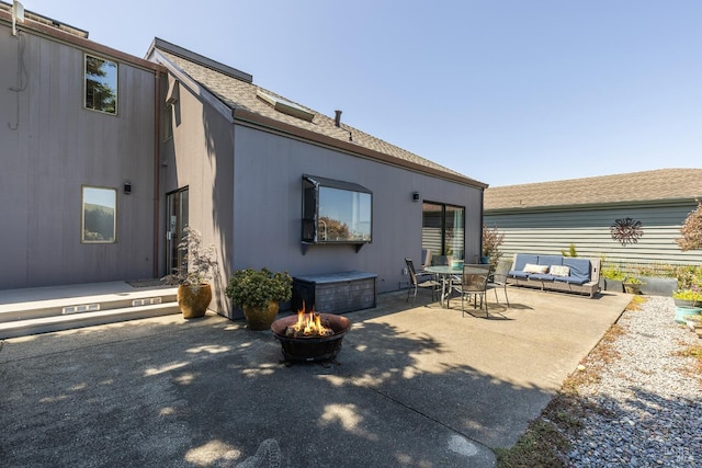 rear view of house featuring a patio and an outdoor living space with a fire pit