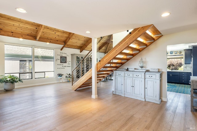 interior space featuring stairway, light wood finished floors, baseboards, wood ceiling, and vaulted ceiling with beams