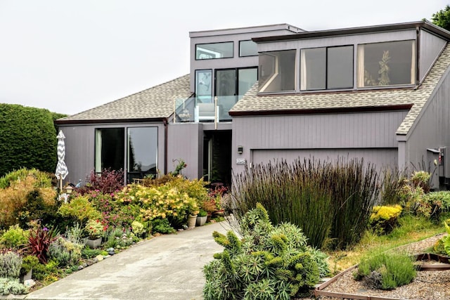 view of front of house featuring concrete driveway and a shingled roof