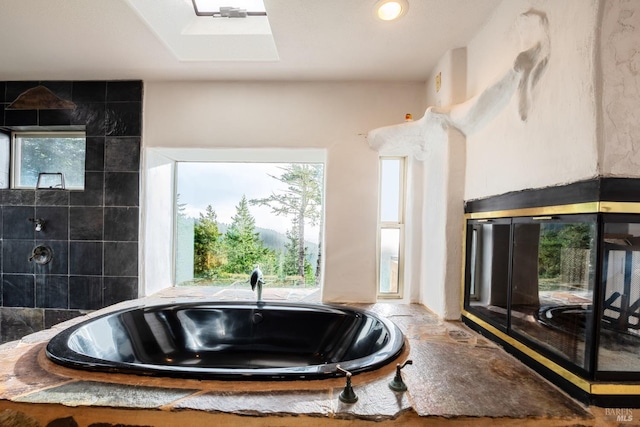 full bath with a skylight and a whirlpool tub