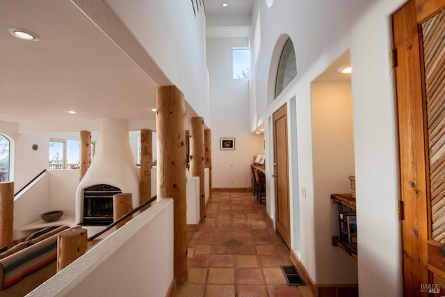 hall featuring visible vents, baseboards, a towering ceiling, an upstairs landing, and recessed lighting