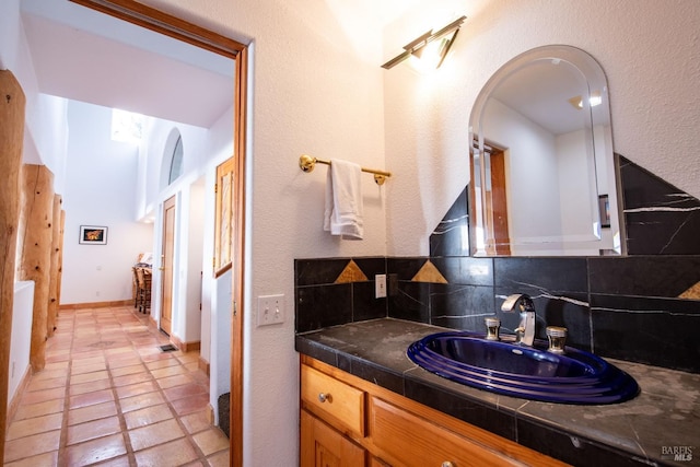 bathroom with tasteful backsplash, tile patterned flooring, vanity, and baseboards