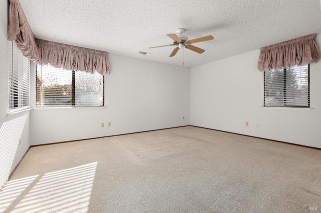 empty room with visible vents, a ceiling fan, carpet flooring, a textured ceiling, and baseboards