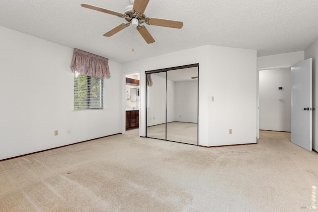 unfurnished bedroom featuring a closet, light colored carpet, connected bathroom, and a textured ceiling