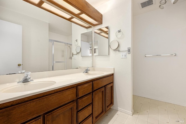 bathroom featuring double vanity, a shower stall, visible vents, and a sink