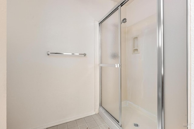 full bathroom with a shower stall and baseboards