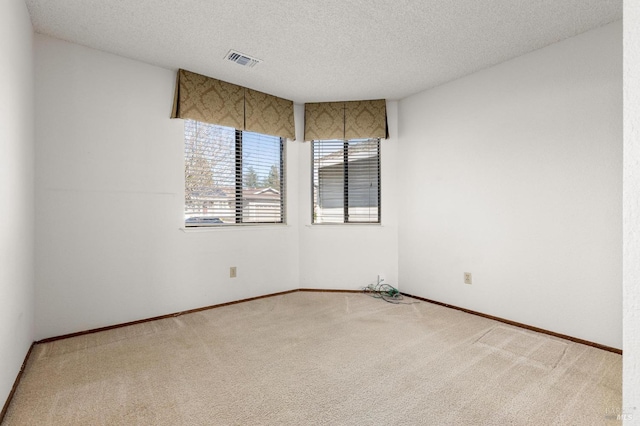 carpeted spare room with visible vents, a textured ceiling, and baseboards