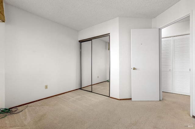 unfurnished bedroom featuring carpet, a closet, a textured ceiling, and baseboards