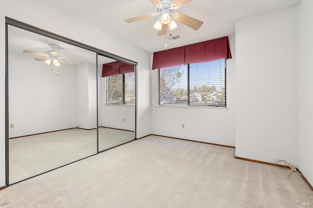 unfurnished bedroom with a textured ceiling, ceiling fan, visible vents, a closet, and carpet