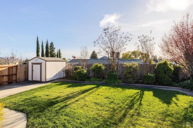 view of yard featuring a storage shed, a fenced backyard, and an outbuilding