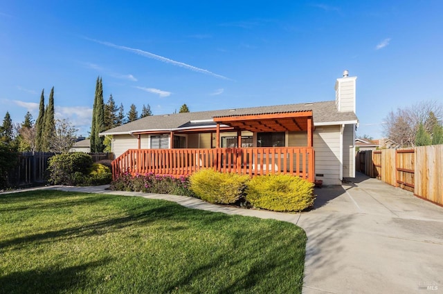 ranch-style house with a chimney, fence, a front lawn, and a wooden deck