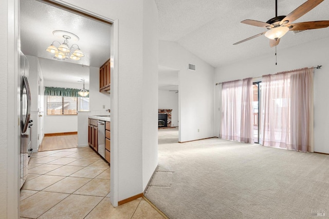 kitchen featuring a textured ceiling, light carpet, visible vents, vaulted ceiling, and appliances with stainless steel finishes