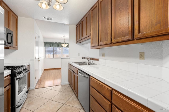 kitchen featuring stainless steel appliances, brown cabinets, visible vents, and a sink