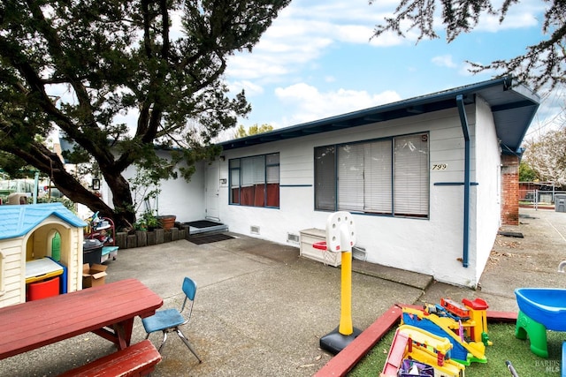 exterior space with crawl space, a playground, a patio, and stucco siding