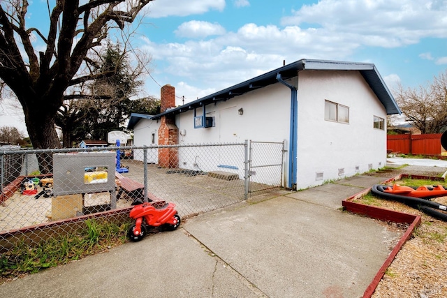 view of home's exterior with crawl space, fence, a gate, and stucco siding