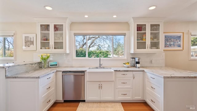 kitchen with dishwasher, a peninsula, a sink, and white cabinets